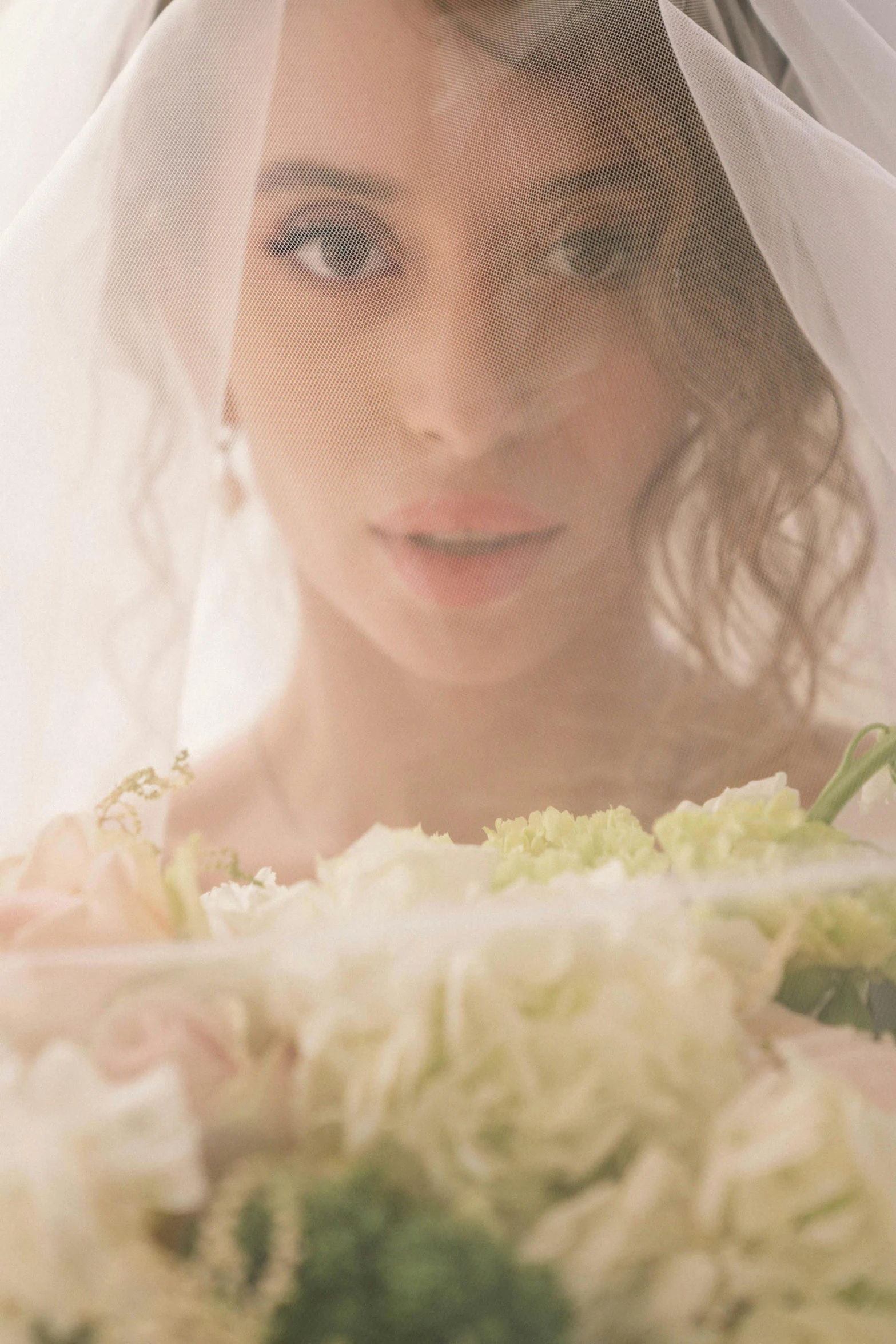 the bride wearing a veil is looking down at her wedding bouquet
