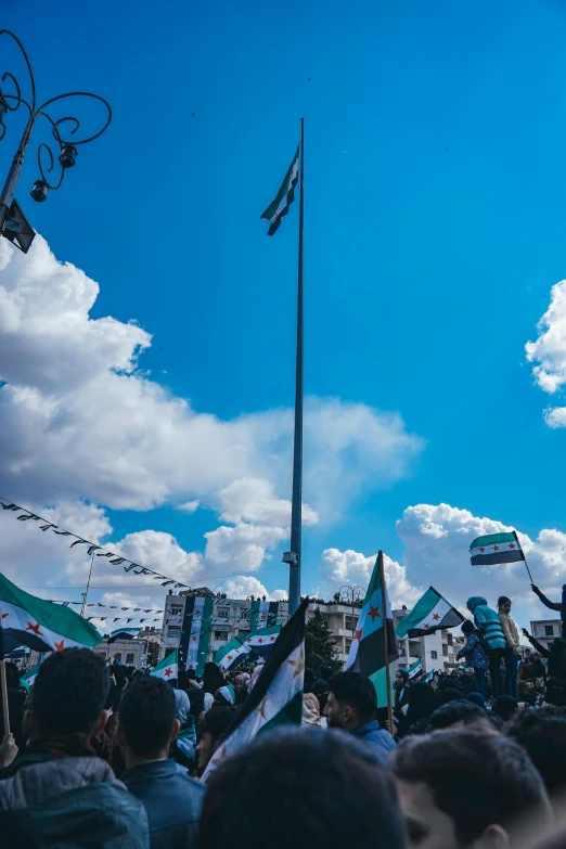 a group of people sitting under the blue sky with two flags