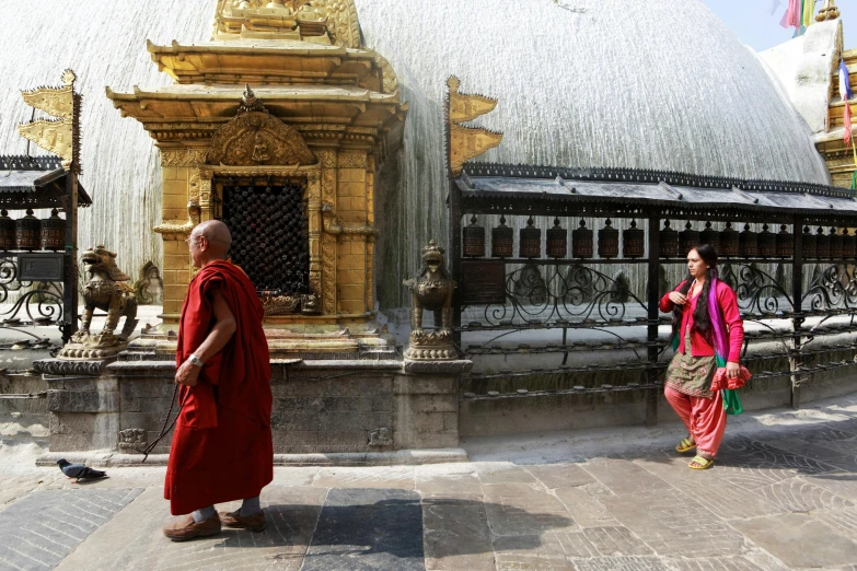 two women with a yellow buddha costume are walking outside