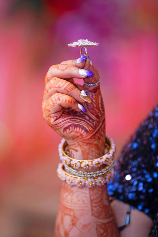 a woman holding up a ring and wearing celets