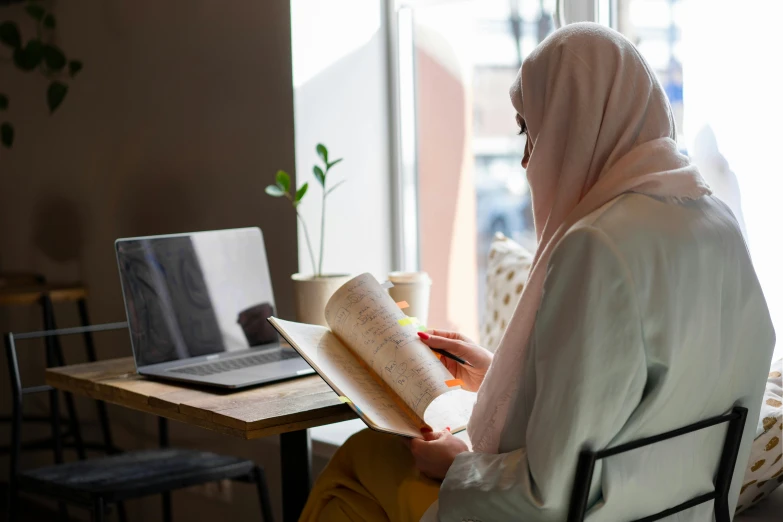 a person sitting at a desk writing on a book