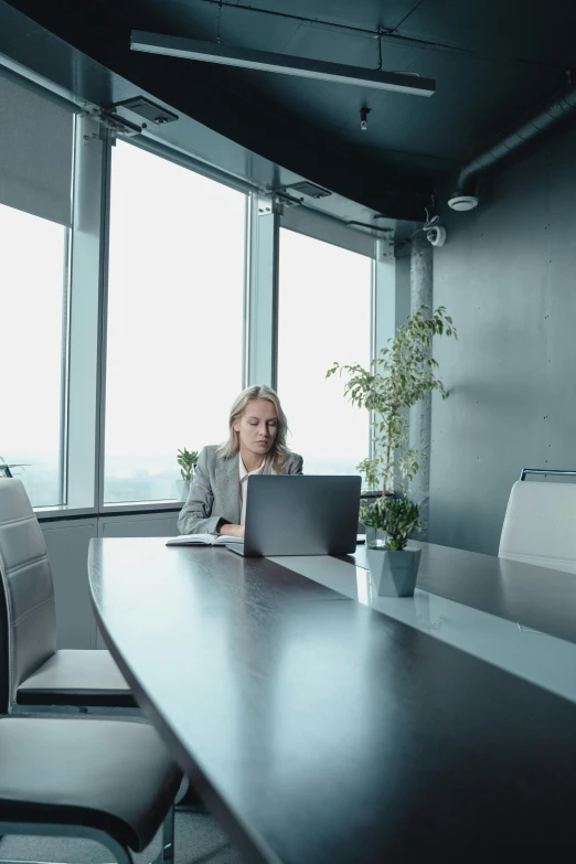 a woman sits at a table on her laptop