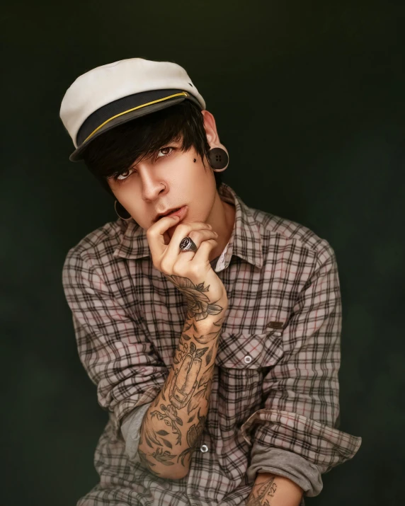 a young man with tattoos sitting down and looking at the camera