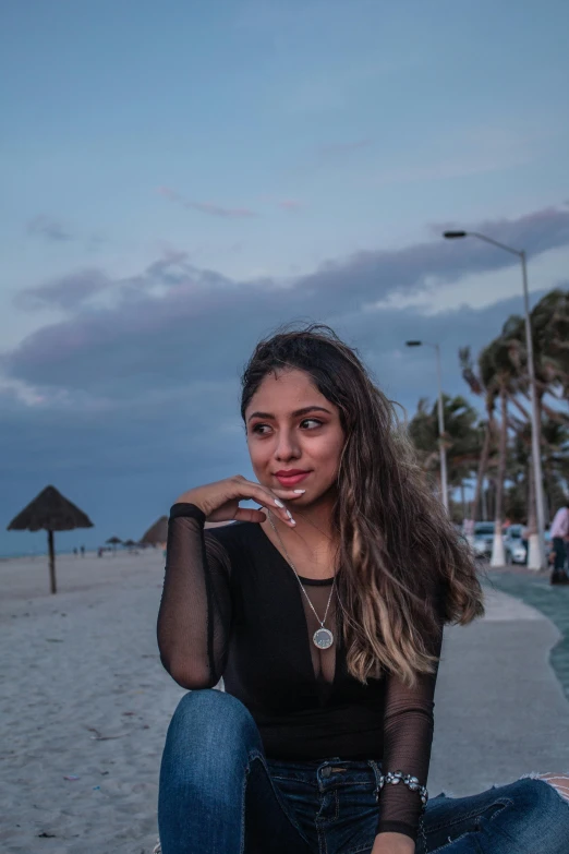 a girl wearing jeans and mesh shirt sitting on concrete