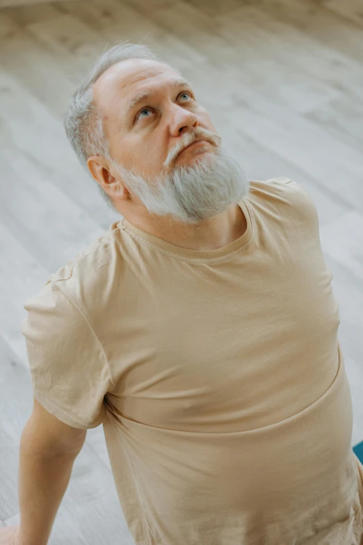 an older man sitting on the ground with his hand on his hip