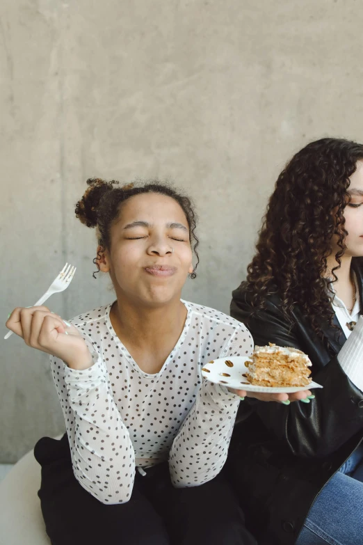 two women sitting down while eating food