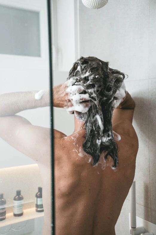 a man washing his hair while looking in the mirror