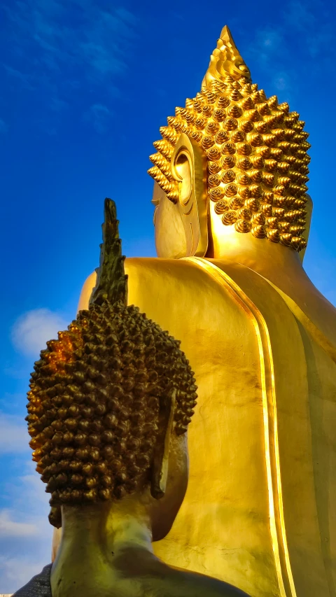 a large golden buddha statue with blue sky in the background