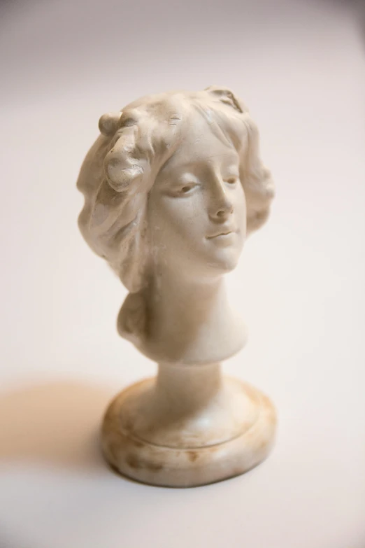 a small white sculpture of a woman's head on a table