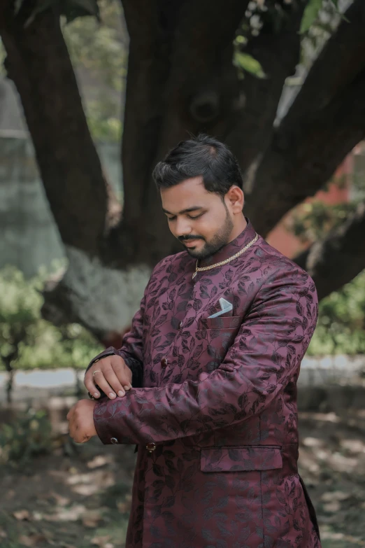 a man wearing an elaborately decorated suit checking his watch