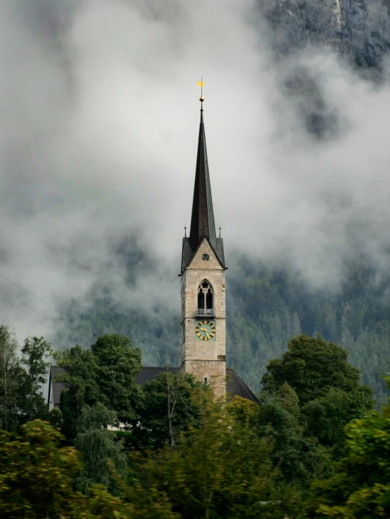 the small steeple of the building overlooks the foggy mountains