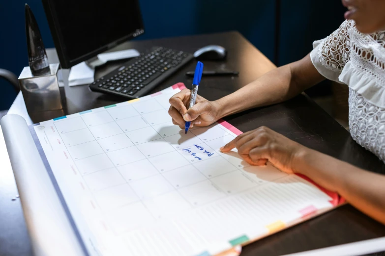 woman writing on notepad with computer keyboard in the background