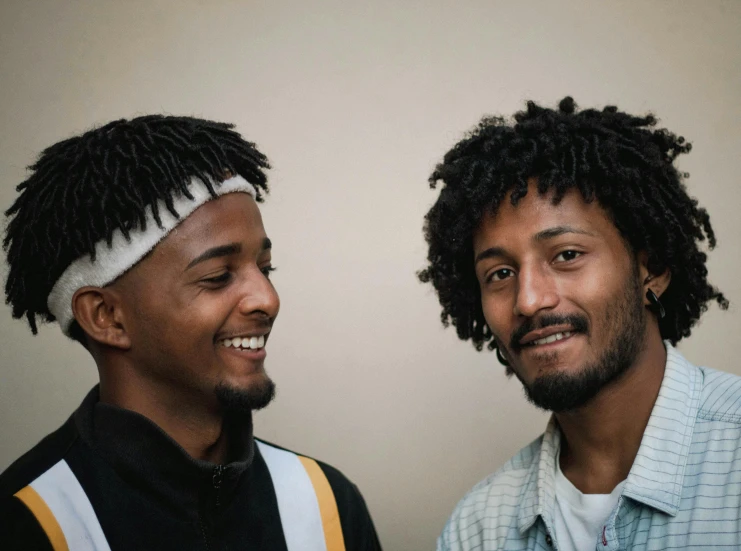 two men standing in front of a white wall smiling