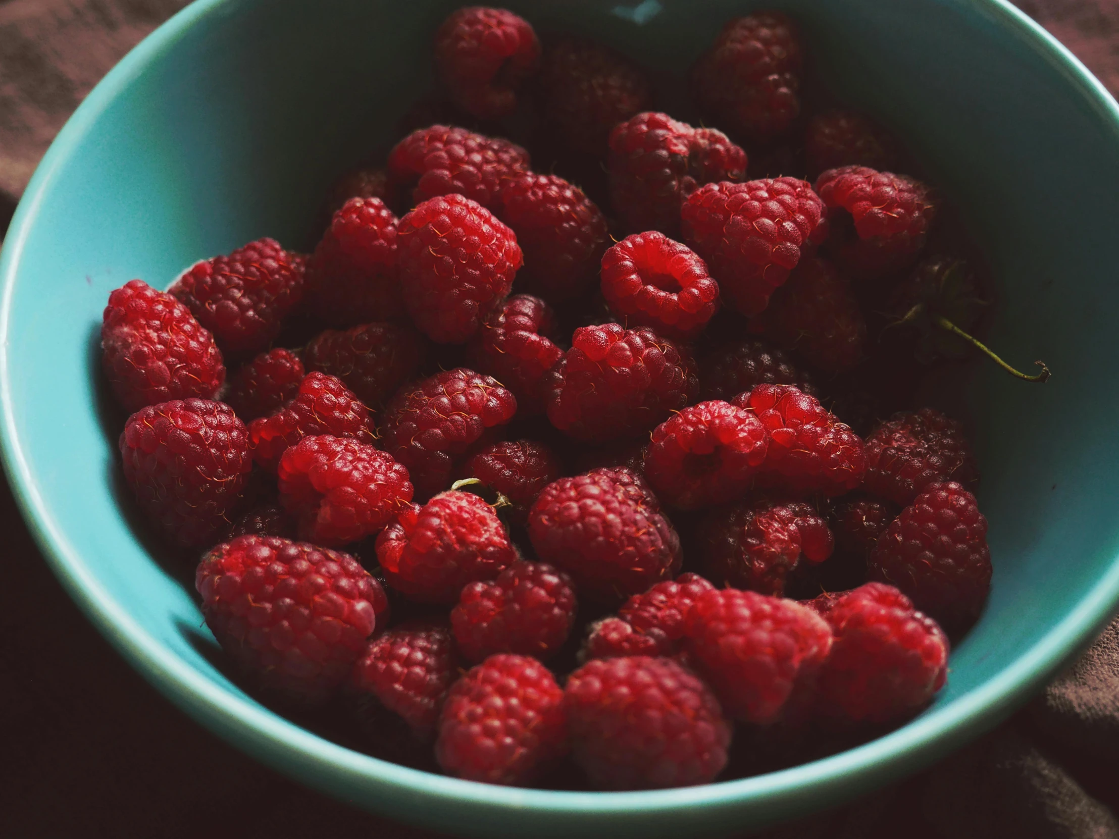 a bowl filled with raspberries on top of a table