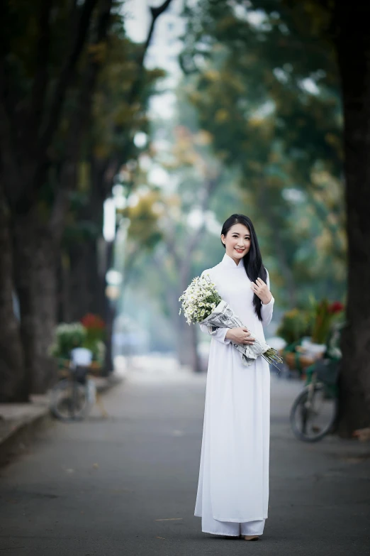 a woman wearing a white gown standing in the street