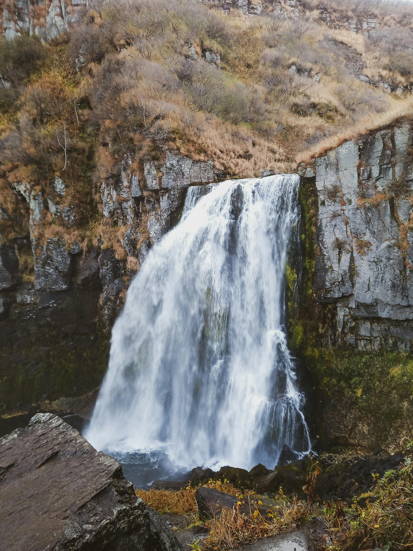 the water is gushing over the rock cliffs