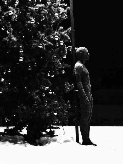 a statue is standing by a christmas tree