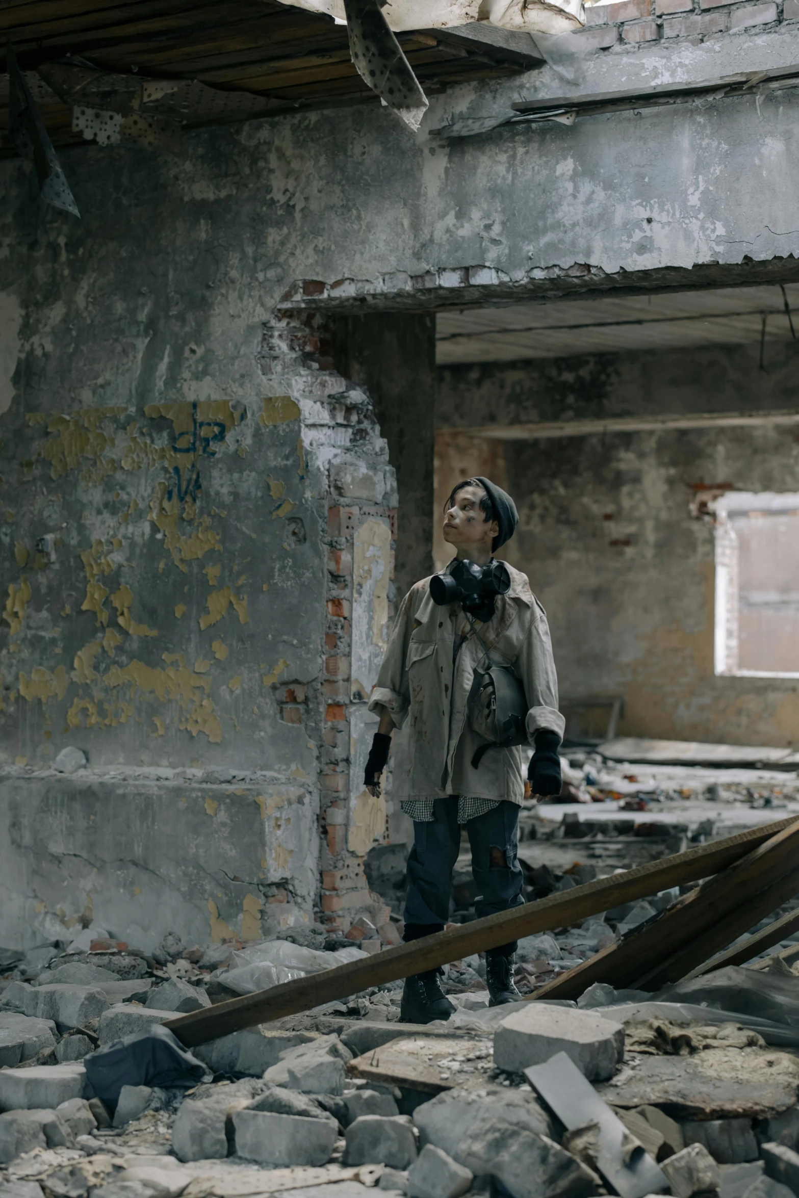 the man in a gas mask stands among rubble