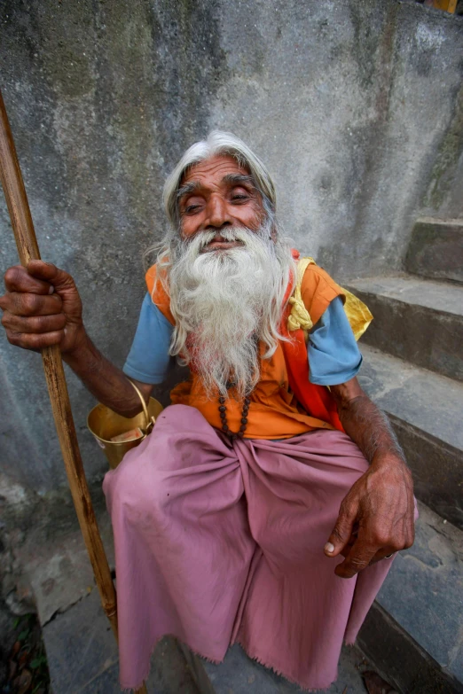 the old man in the orange vest is holding a stick