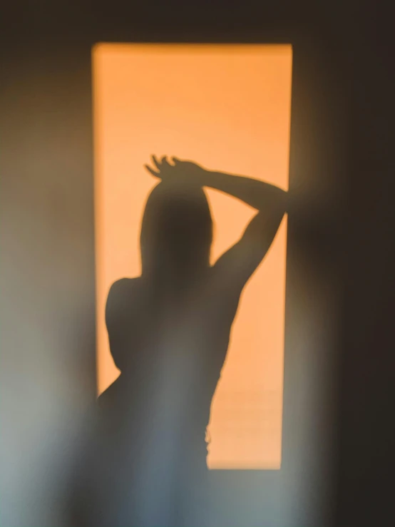 a woman in silhouette holding her arms up and looking through a window