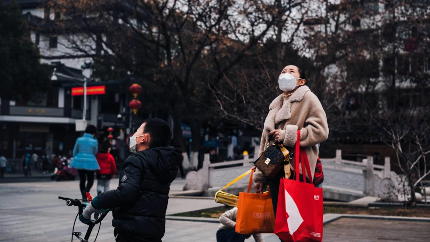 people are walking with colorful bags and a man wearing a mask