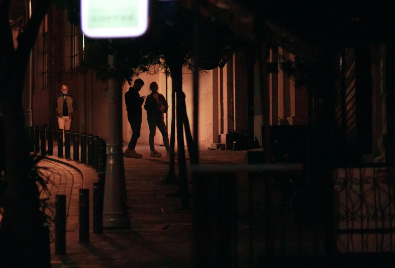 two people standing on a street corner, at night