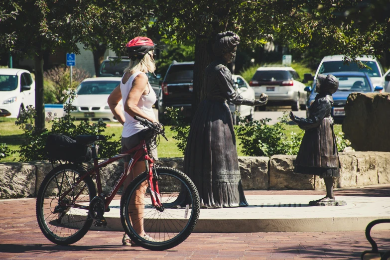 a woman is riding a bicycle by the statue of a pharaoh and a child