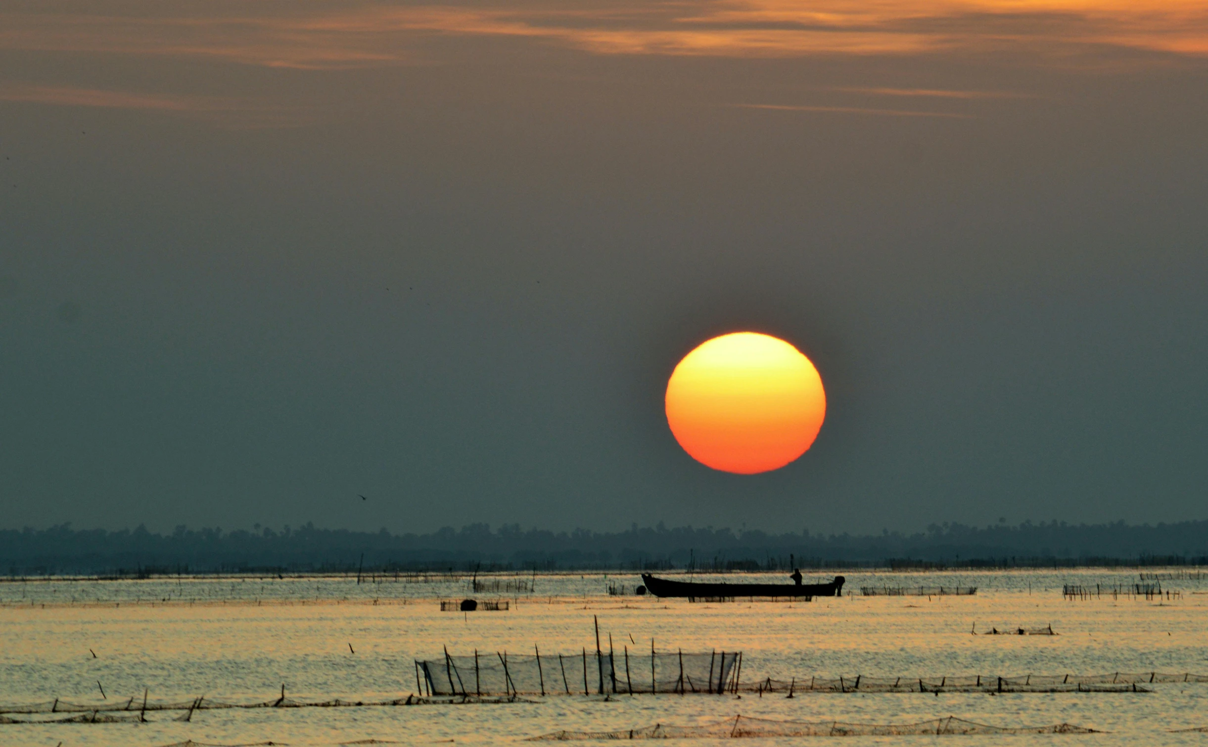 a view of some water with a boat and the sun going down