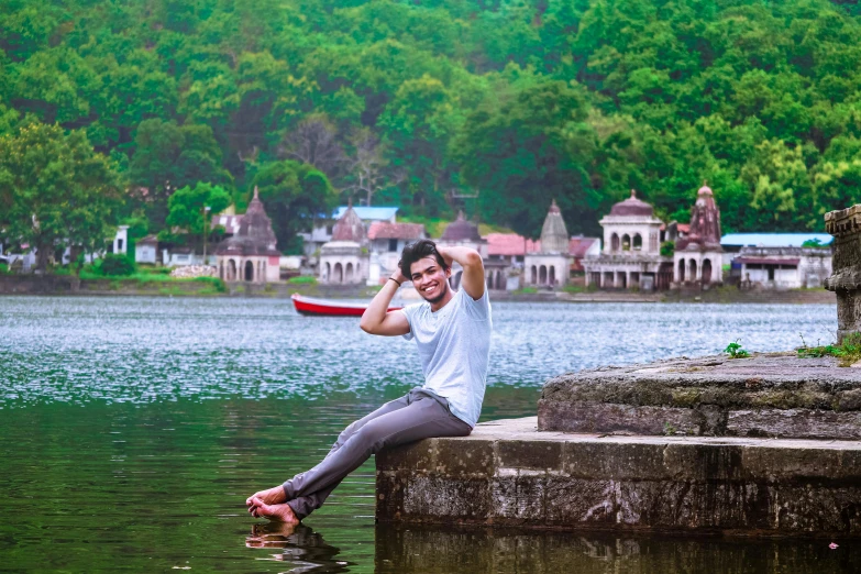 a man posing on top of a pier next to a body of water