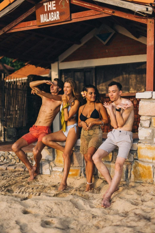 men and women posing on the sand of a beach