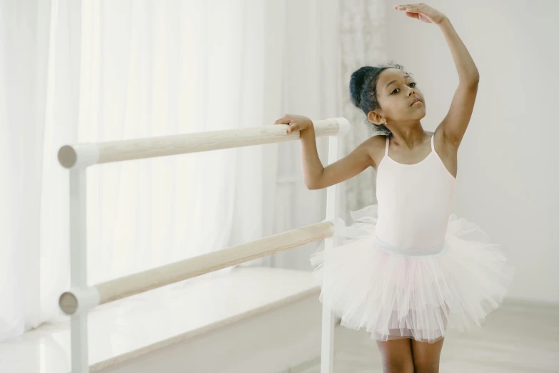 young ballerina in pink tutu leaning against rail