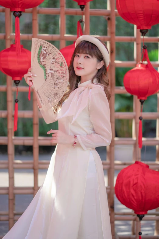 a woman in a long white dress holding a fan