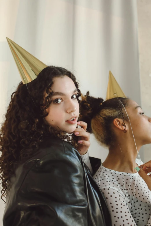 a woman is wearing gold party hats as a girl stands in front of her
