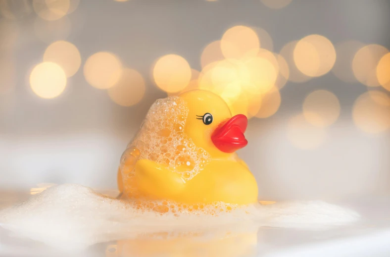 the toy rubber duck sits in the foamy water