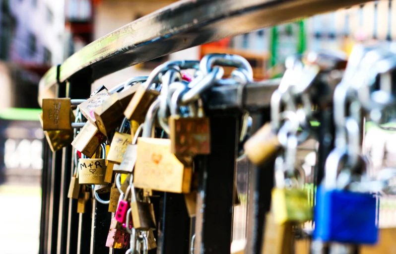 combination locks with different colors are attached to a fence