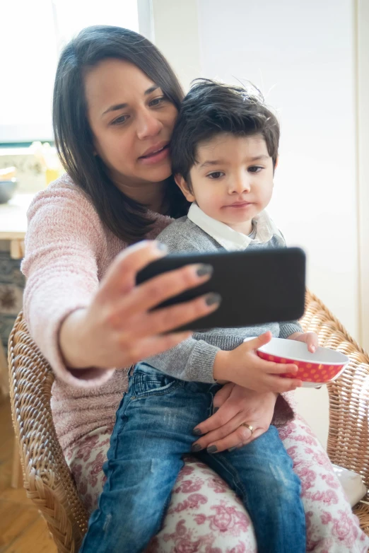 a woman holding a small child taking a picture