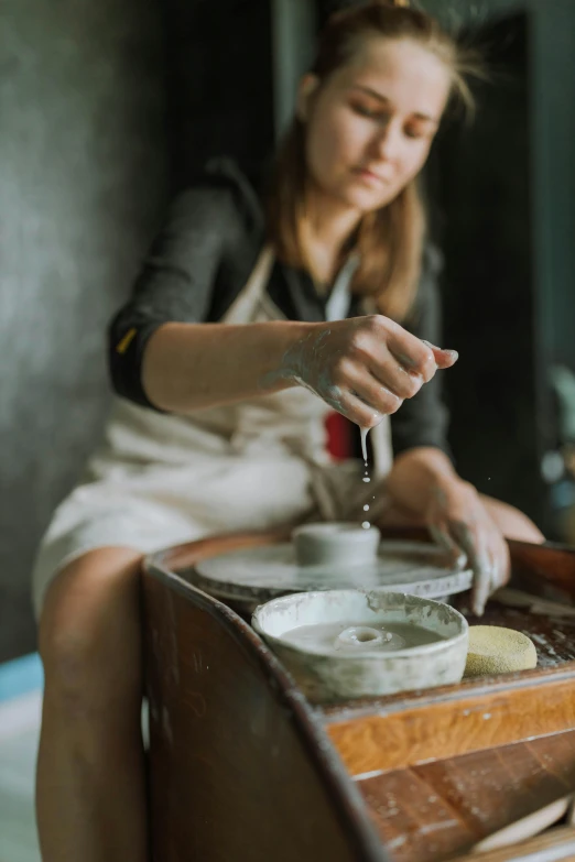 a woman sitting on a counter and putting some liquid in her cup