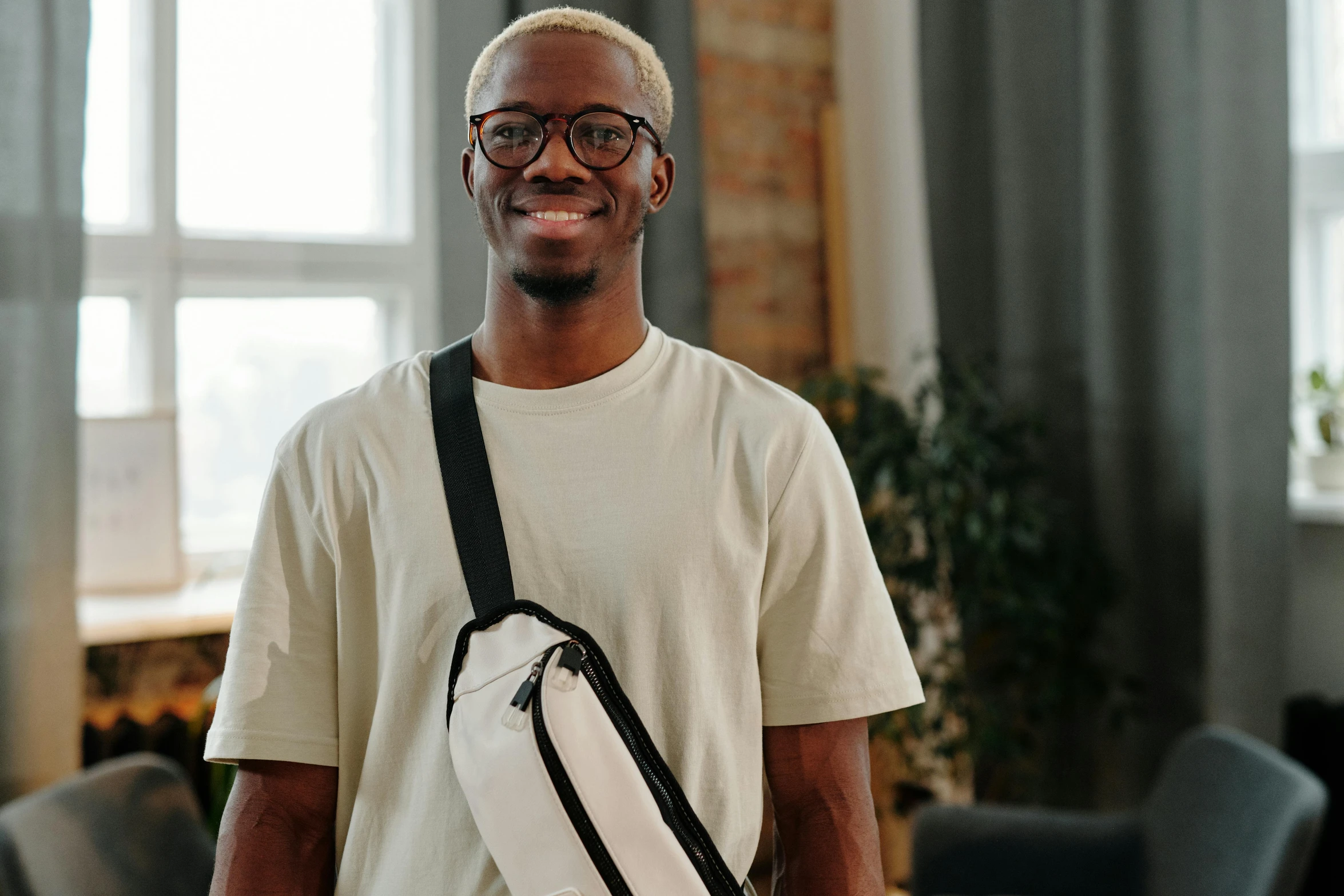 smiling man in white shirt holding black and white sports bag