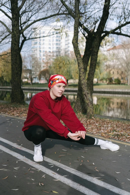 a young man in red jacket sitting down next to a park