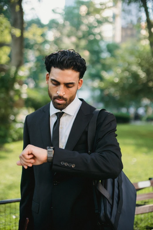 a man dressed in a suit and tie checks his watch