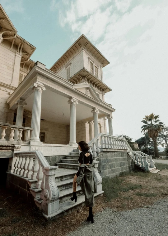 an antique building with an old woman walking towards the doorway