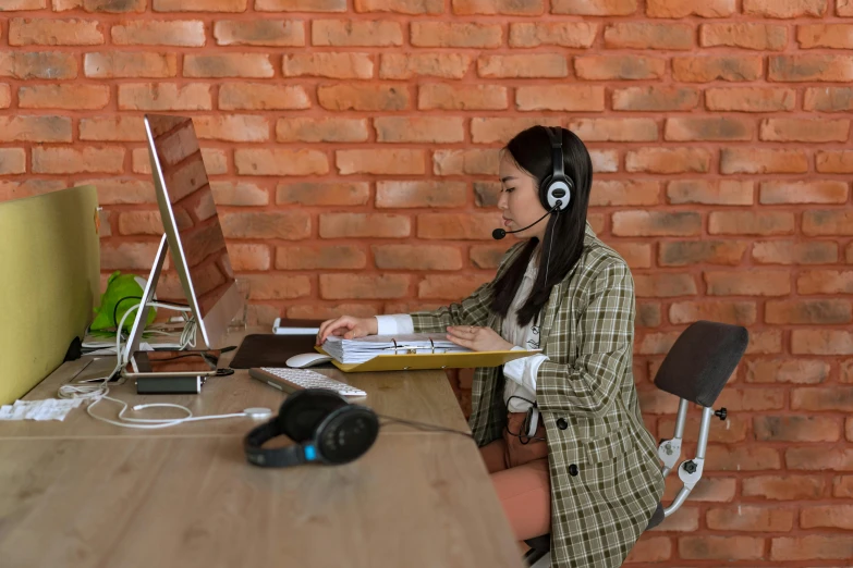 a young woman sitting at a desk in front of a monitor with headphones