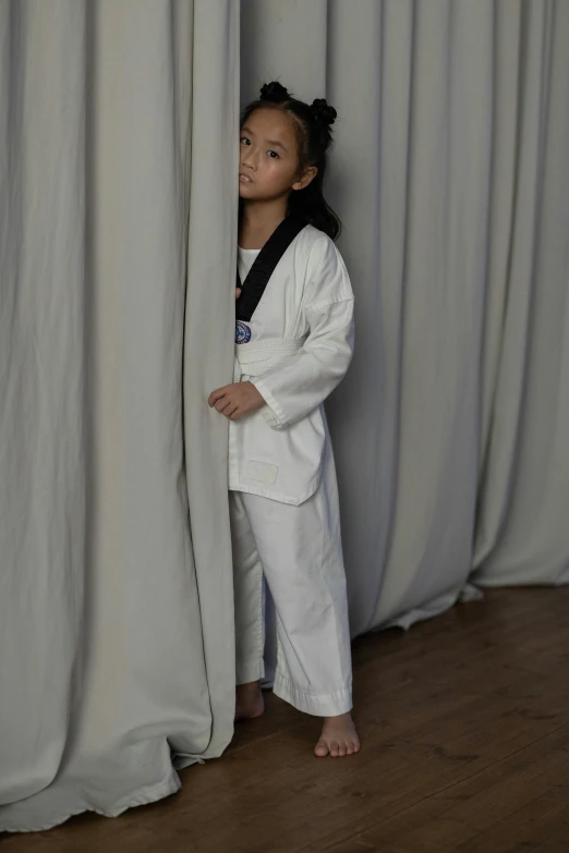 a child is holding curtains up and waiting