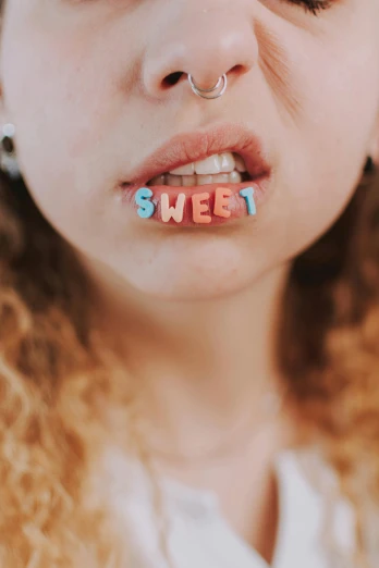 a girl wearing letters on her nose with a nose piece saying sweet