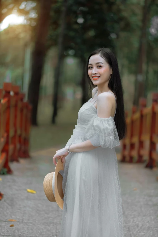 a woman in an all white gown with her hair half up and a straw hat on