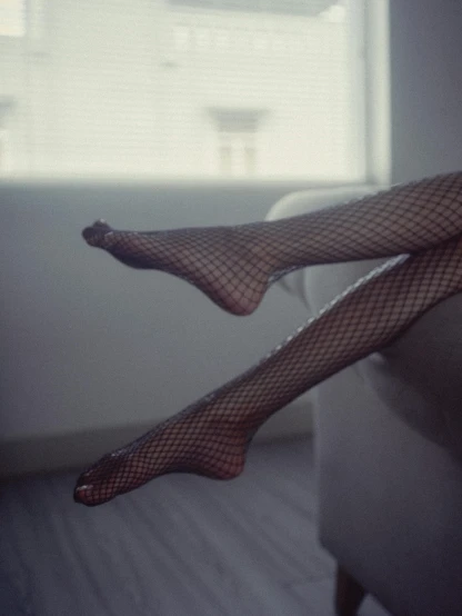 woman in fishnet stockings sitting on a bed