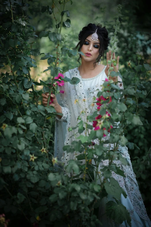 a woman in white holding flowers with a tiara on