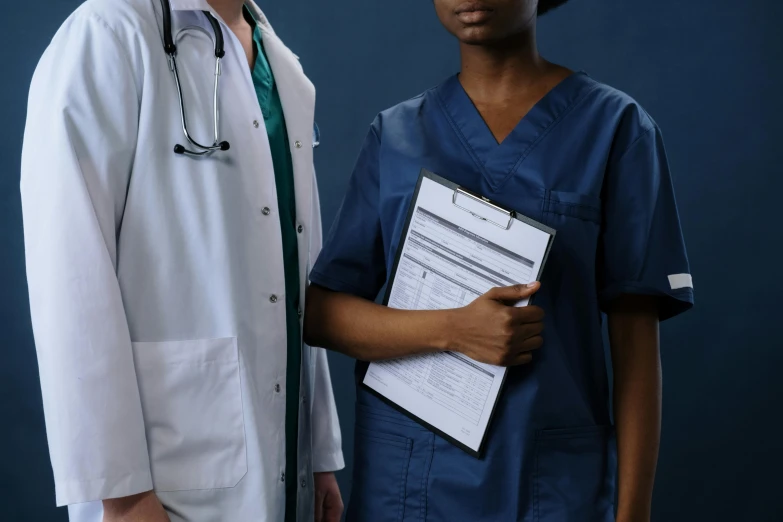 two young men in scrubs one is holding a clipboard