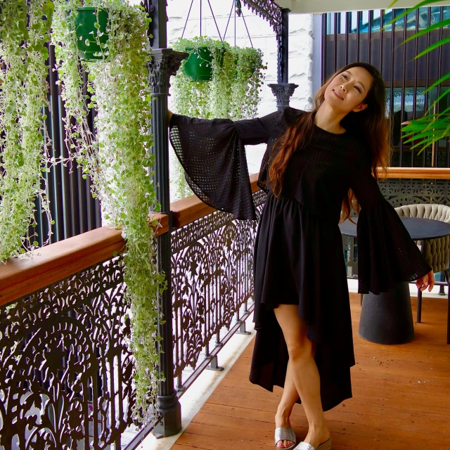 the woman is posing on a balcony near some plants