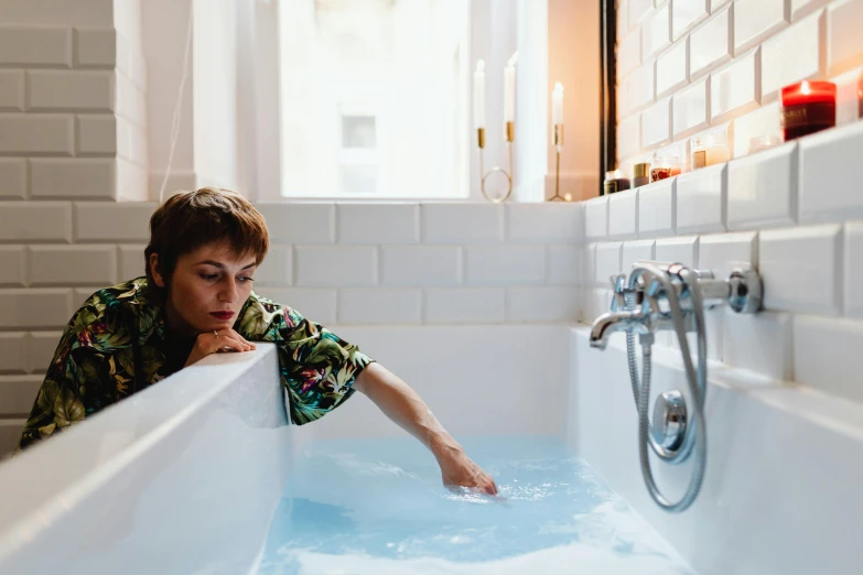 a woman in the bathtub staring up and touching the edge